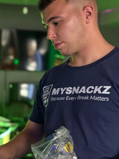 Merwan Unvar, Inhaber von MYSNACKZ, am geöffneten Snackautomaten