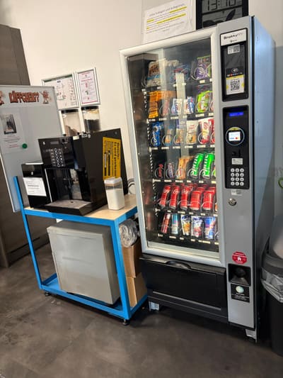 Gemieteter Snackautomat von MYSNACKZ im Pausenraum, eine Person entnimmt einen Snack